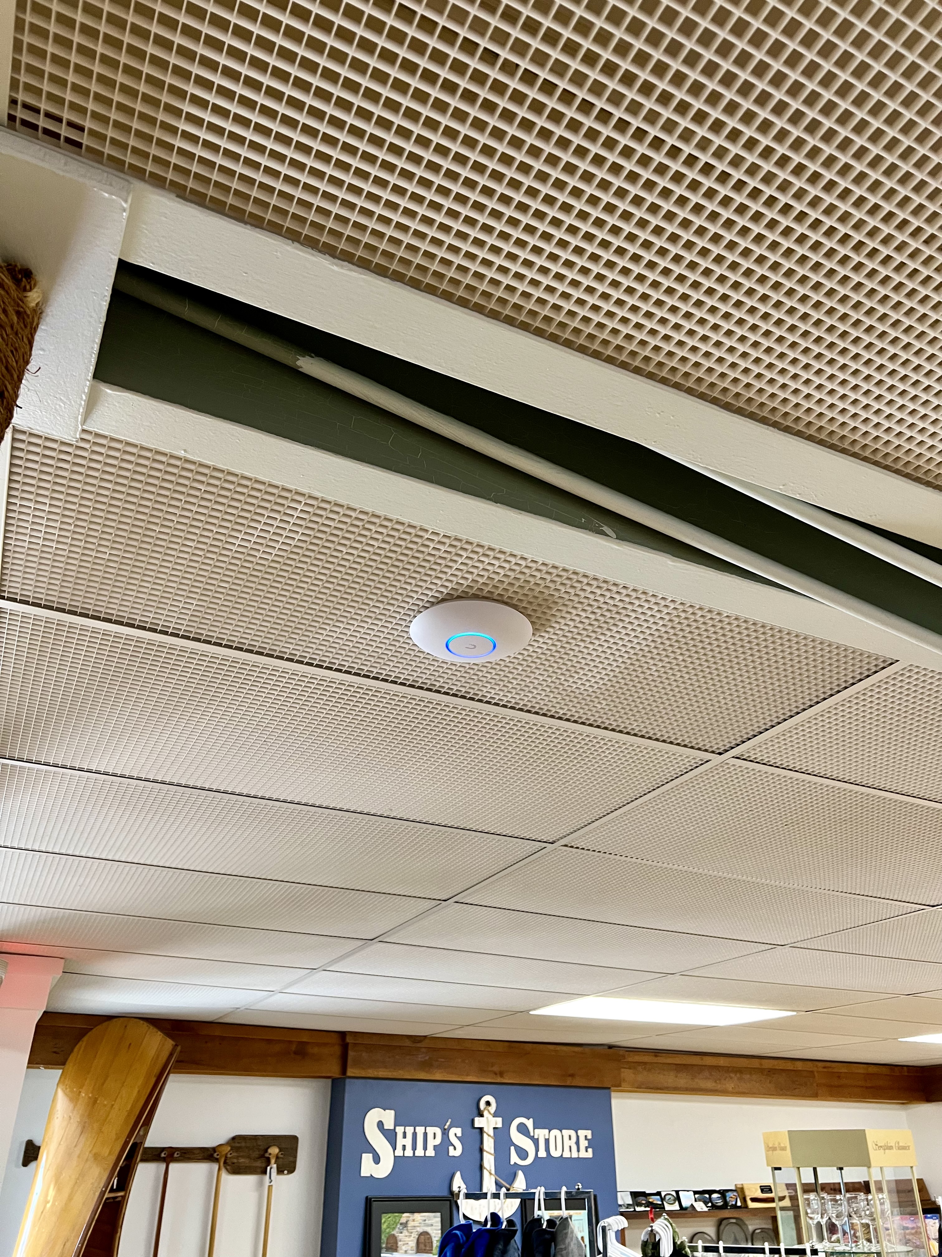 UniFi access point installed in drop ceiling above ship's store